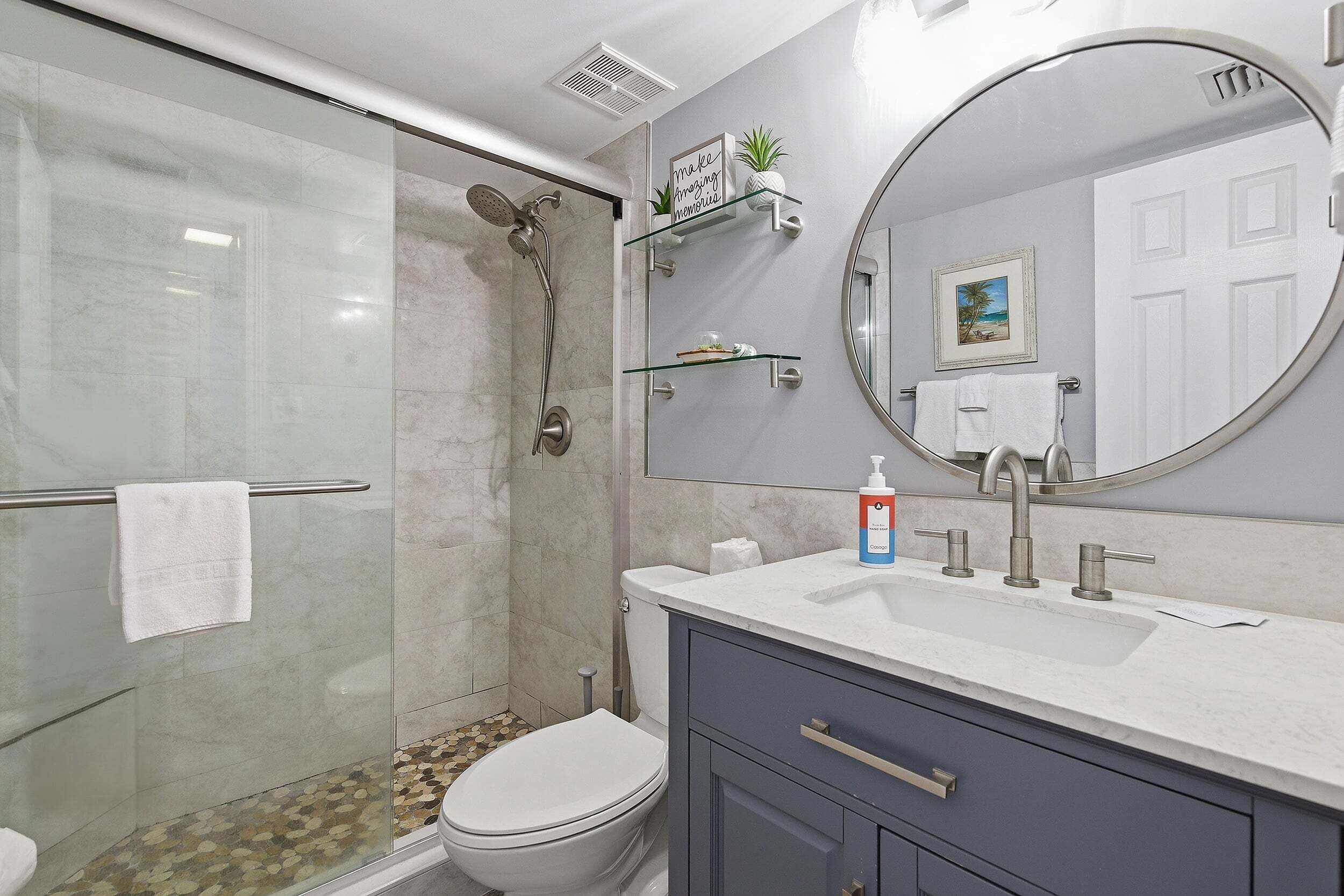 Un bagno con cabina doccia in vetro, un water, un lavandino con specchio e un mobile contenitore con cassetti.
