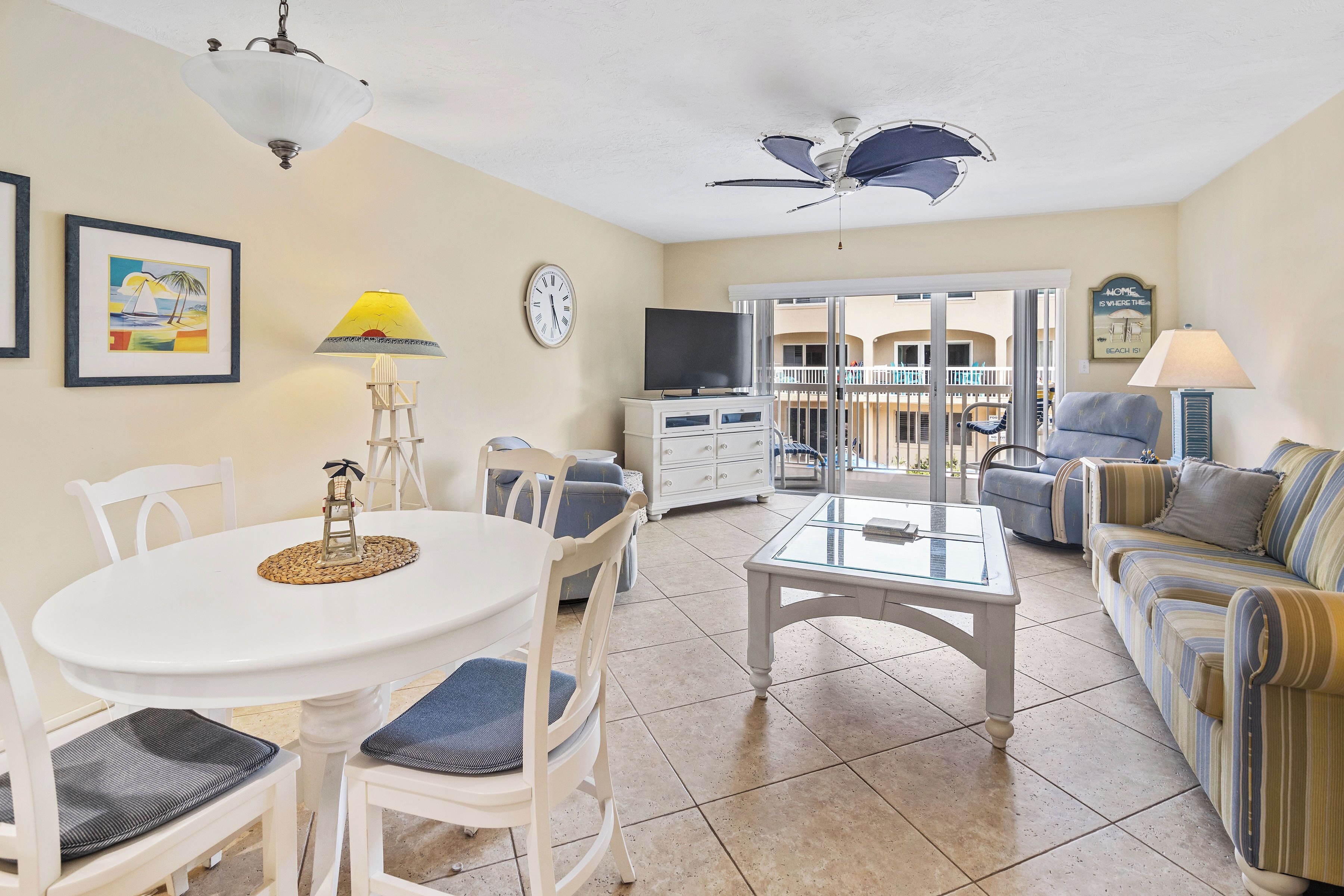 A living room with a dining table, chairs, a sofa, a TV, and a ceiling fan.