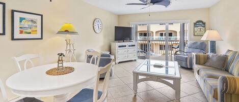 A living room with a dining table, chairs, a sofa, a TV, and a ceiling fan.
