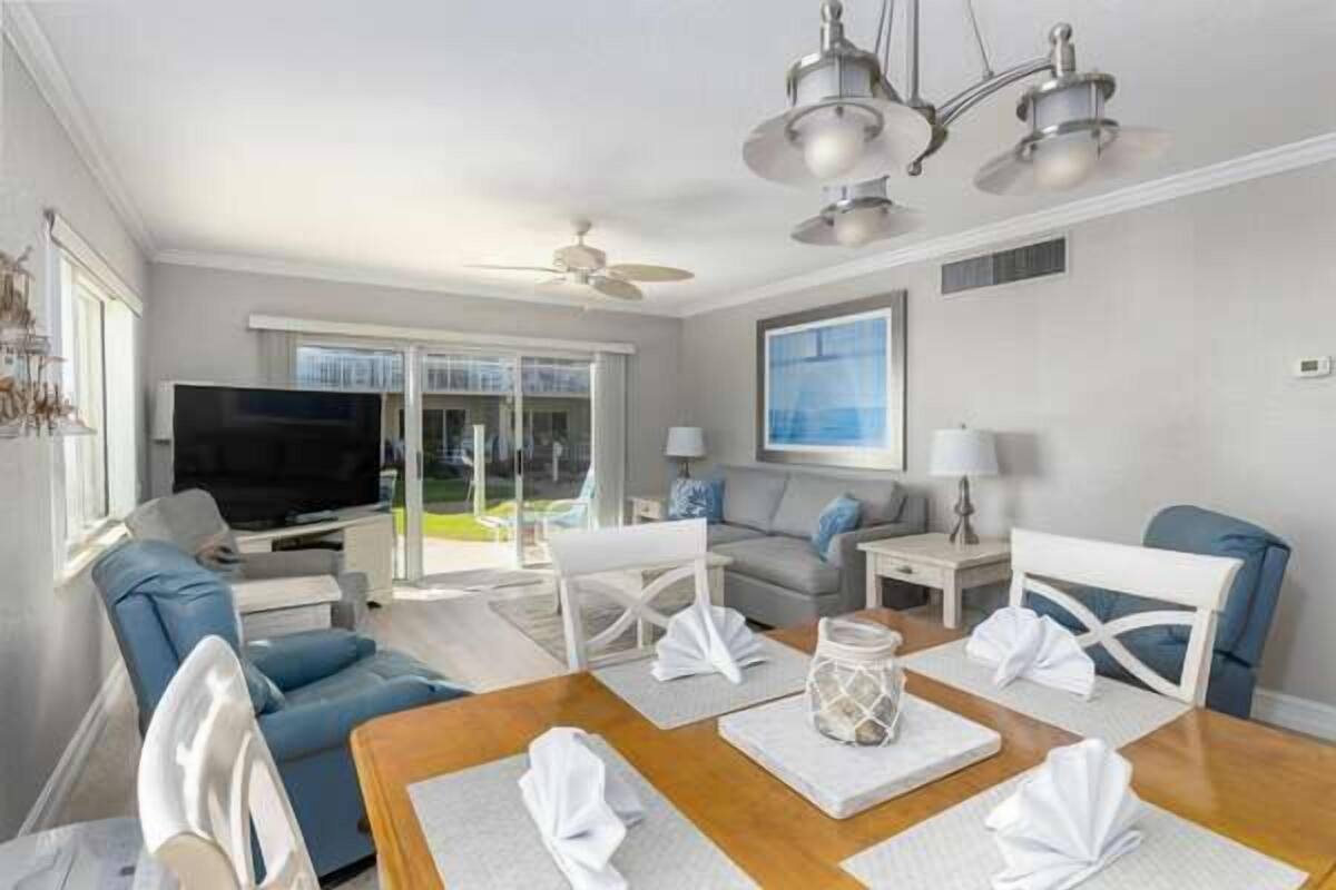A modern living room with a sofa, chairs, a dining table, and a TV.