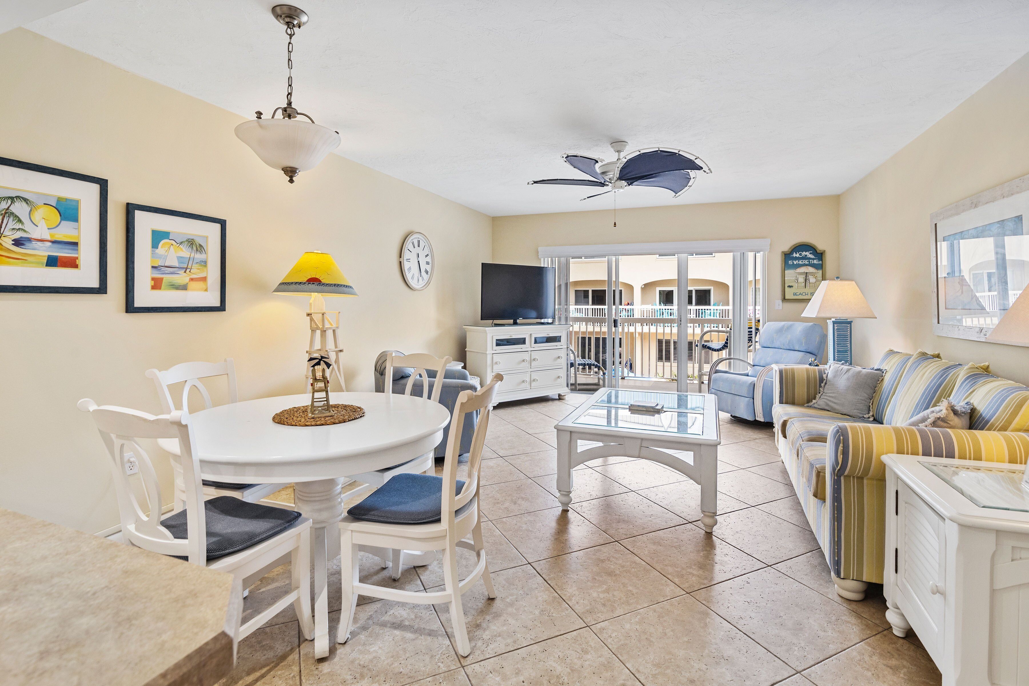 A well-lit living room with a dining area, a TV, and a balcony with a view.