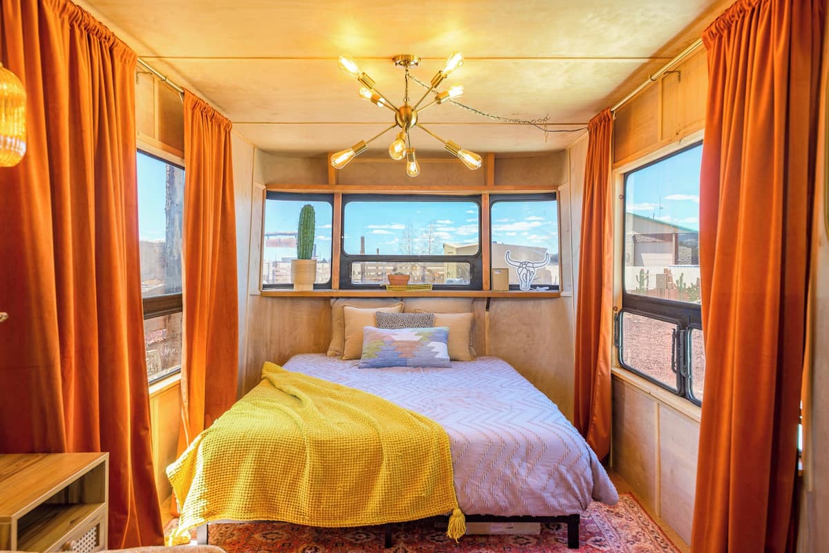 Un dormitorio acogedor con cama, ventana con un cactus y una lámpara en el techo.
