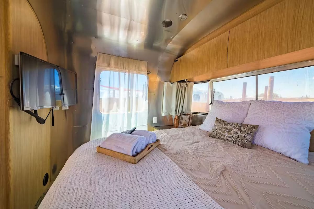 Una habitación acogedora con una cama, un televisor y un ventanal con cortinas.