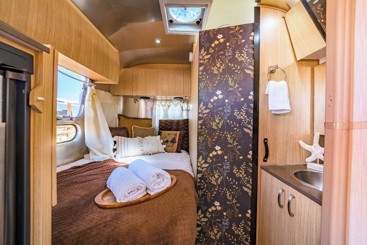 Un interior de autocaravana acogedor, con una cama, una pequeña cocina y un baño.
