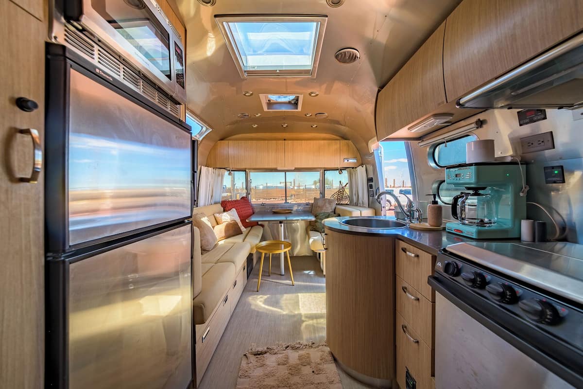 Una cocina compacta para vehículos recreativos con una isla central, un refrigerador y una estufa.