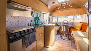 Cocina compacta para vehículos recreativos, con estufa, cafetera y un pequeño comedor.