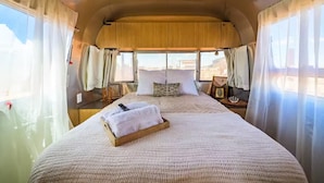 Interior acogedor de una autocaravana con una cama, cortinas y una ventana.
