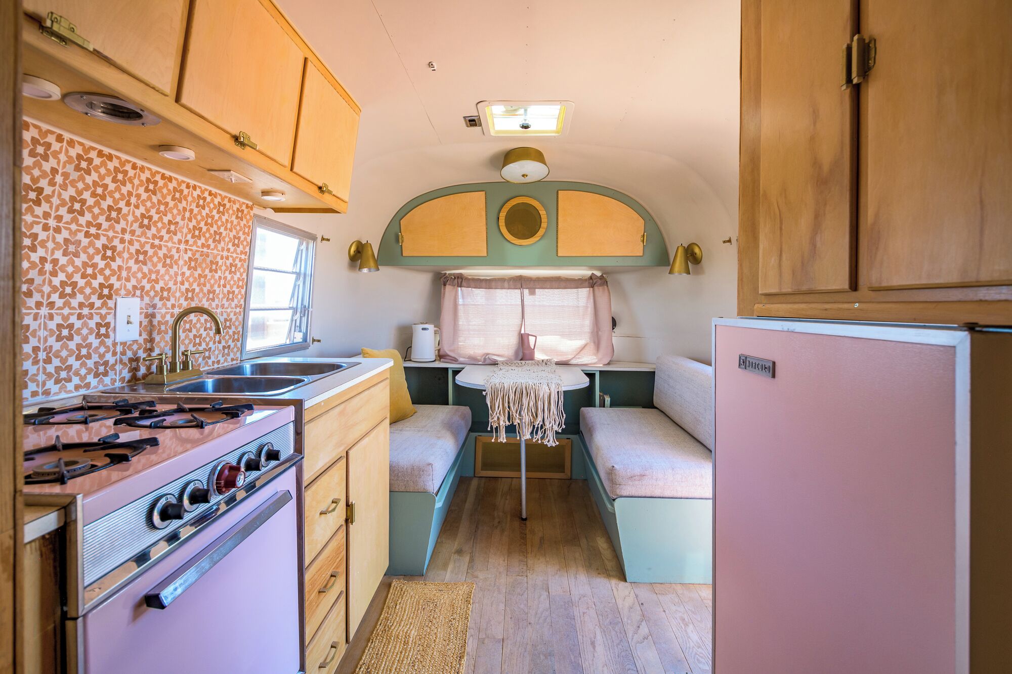 A compact RV kitchen with a stove, sink, and refrigerator.