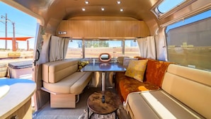 Interior acogedor de una caravana con comedor, asientos y vistas al exterior.