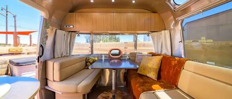 Interior acogedor de una caravana con comedor, asientos y vistas al exterior.