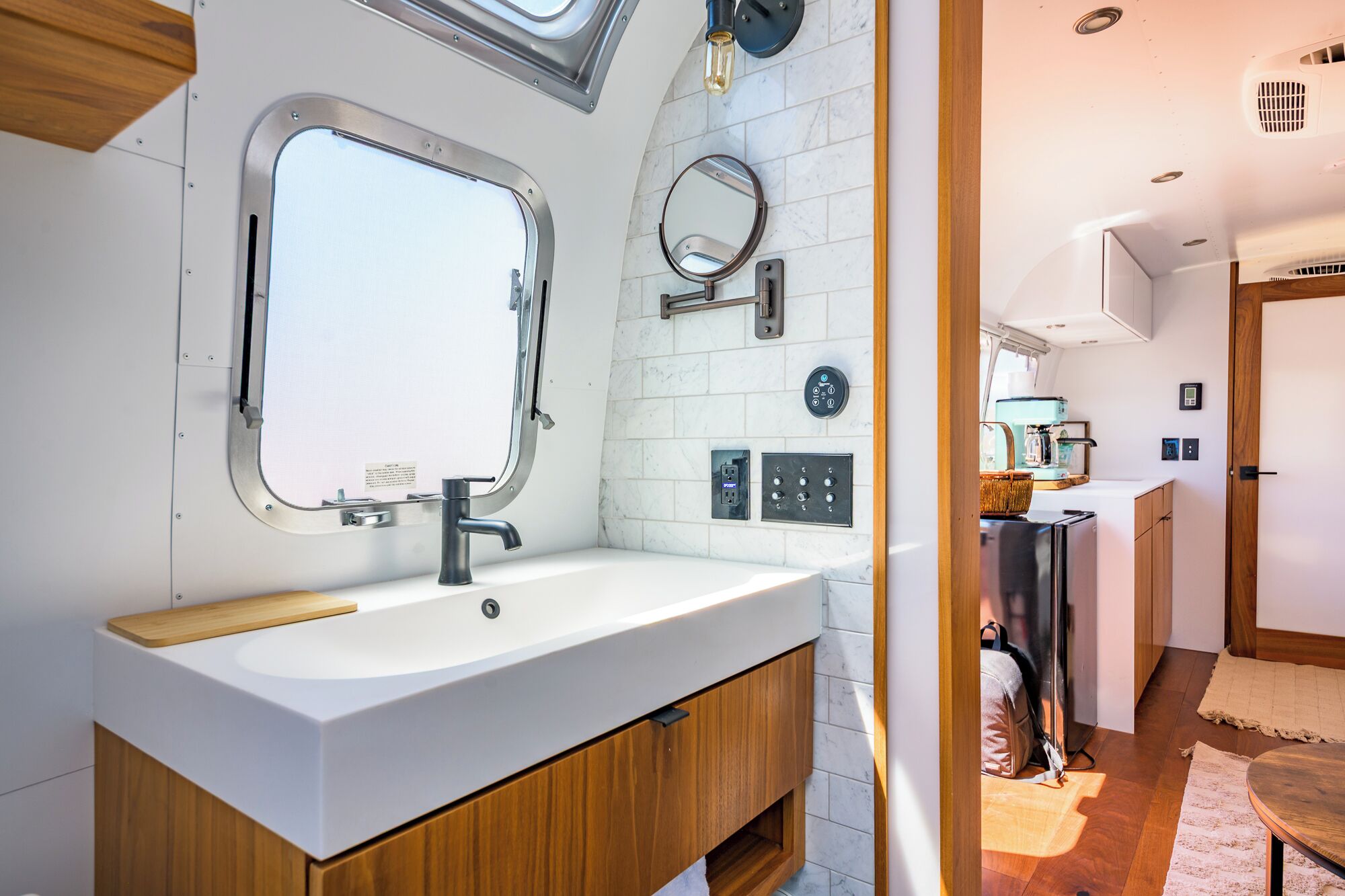 Een moderne badkamer met een grote spiegel, een wastafel en een houten wastafelmeubel.
