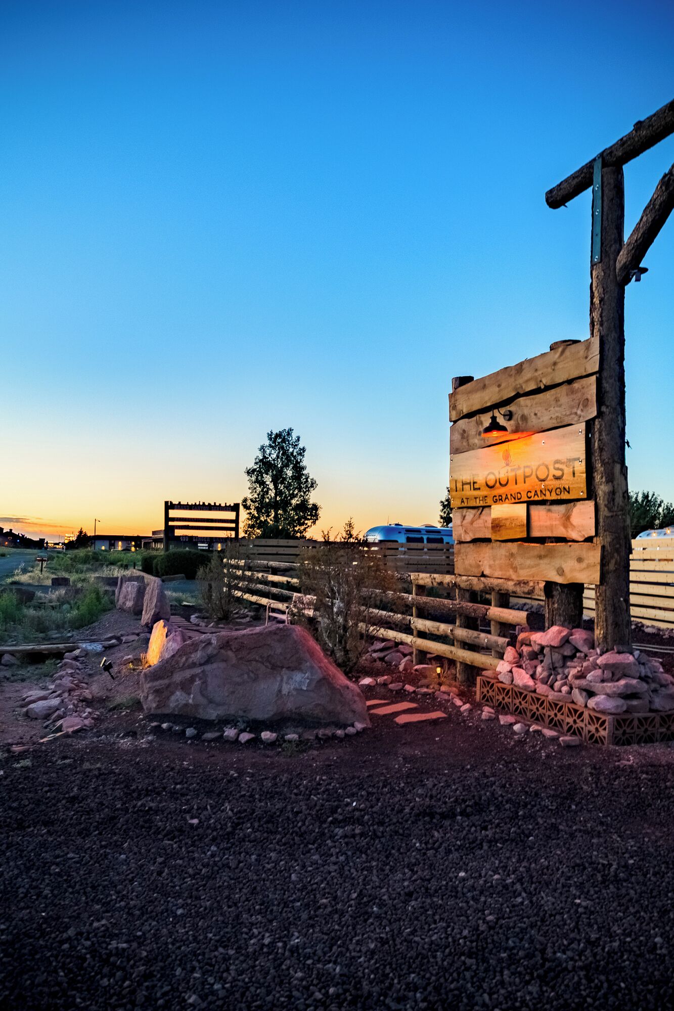 A wooden sign with text, a rustic fence, and a clear sky.