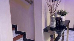 A staircase with marble steps and a handrail, leading to a landing with a black console table and decorative items. - KUMASI's SECRET II (Juahaw)