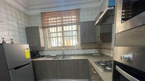 Eine Küche mit Kühlschrank, Herd, Spüle und einem Fenster mit Jalousien.