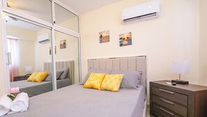 A bedroom with a bed, bedside tables, a mirror, and an air conditioner. - Edificio Amber (San Cristobal)