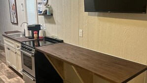 Una cocina con encimera de madera, electrodomésticos de acero inoxidable y televisión montada en la pared.