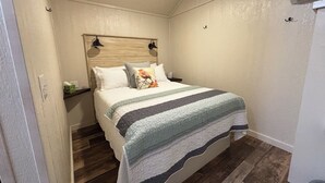 A bedroom with a bed, wooden headboard, bedside tables, and a ceiling fan.