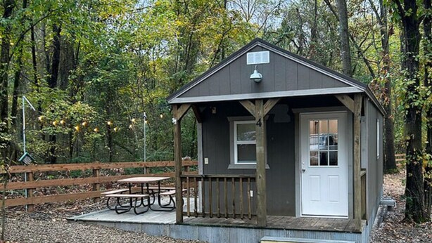 A small cabin with a porch, a door, and a window.