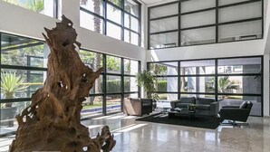 A spacious lobby with large windows, a central wooden sculpture, and a seating area with sofas. - Urbano Duplex by WECARE Hosting (São Paulo)