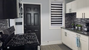 A modern kitchen with a black stove, white cabinets, and a black pendant light. - Zen Den Getaway, your peaceful retreat near Cleveland’s vibrant AsiaTown. (Cleveland)