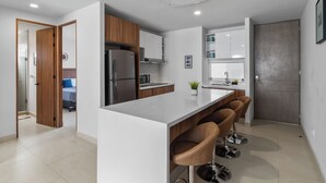 Une cuisine moderne dotée d’un îlot central, de meubles en bois et d’un réfrigérateur en acier inoxydable.