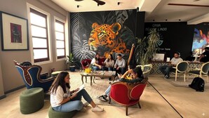 Un área de lounge moderna con un gran mural de un leopardo, asientos cómodos y una pantalla de proyección que muestra 'CASA MEXICO LINDO'.