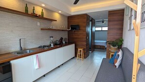 Una cocina moderna con encimera de madera, electrodomésticos integrados y una zona de comedor con sofá y una mesita.