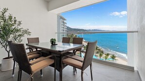 A balcony with a glass table and chairs, overlooking a beach and ocean. - Beachfront, luxurious, with amazing view (Puerto Vallarta)