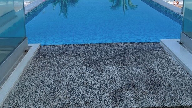 A clear blue infinity pool with palm trees on either side, leading to the ocean. - Beachfront, luxurious, with amazing view (Puerto Vallarta)