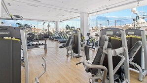 A gym with cardio machines, weight stations, and a view of the cityscape through large windows. - Marina Vallarta with View and Pool (Puerto Vallarta)