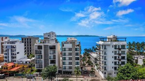 A coastal residential area with modern apartment buildings, some with balconies, and a clear view of the sea. - One block from the beach in Bucerias (Bucerías)