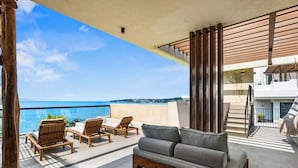 A balcony with wicker furniture, a grey sofa, and a view of the ocean. - One block from the beach in Bucerias (Bucerías)
