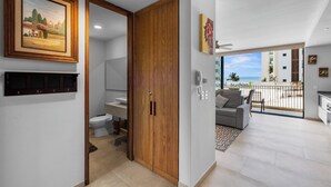 A modern hotel room with a wooden door, a bathroom with a toilet and sink, a balcony with a view of the ocean, and a painting on the wall. - One block from the beach in Bucerias (Bucerías)