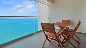 A balcony with a wooden table and chairs, overlooking a clear blue sea and a distant ship. - Magnificent view from the floor 26 (Puerto Vallarta)