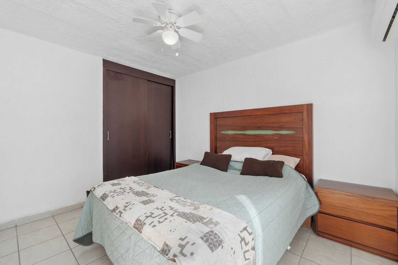 Camera da letto con un letto, una testiera in legno, comodini e un ventilatore a soffitto.