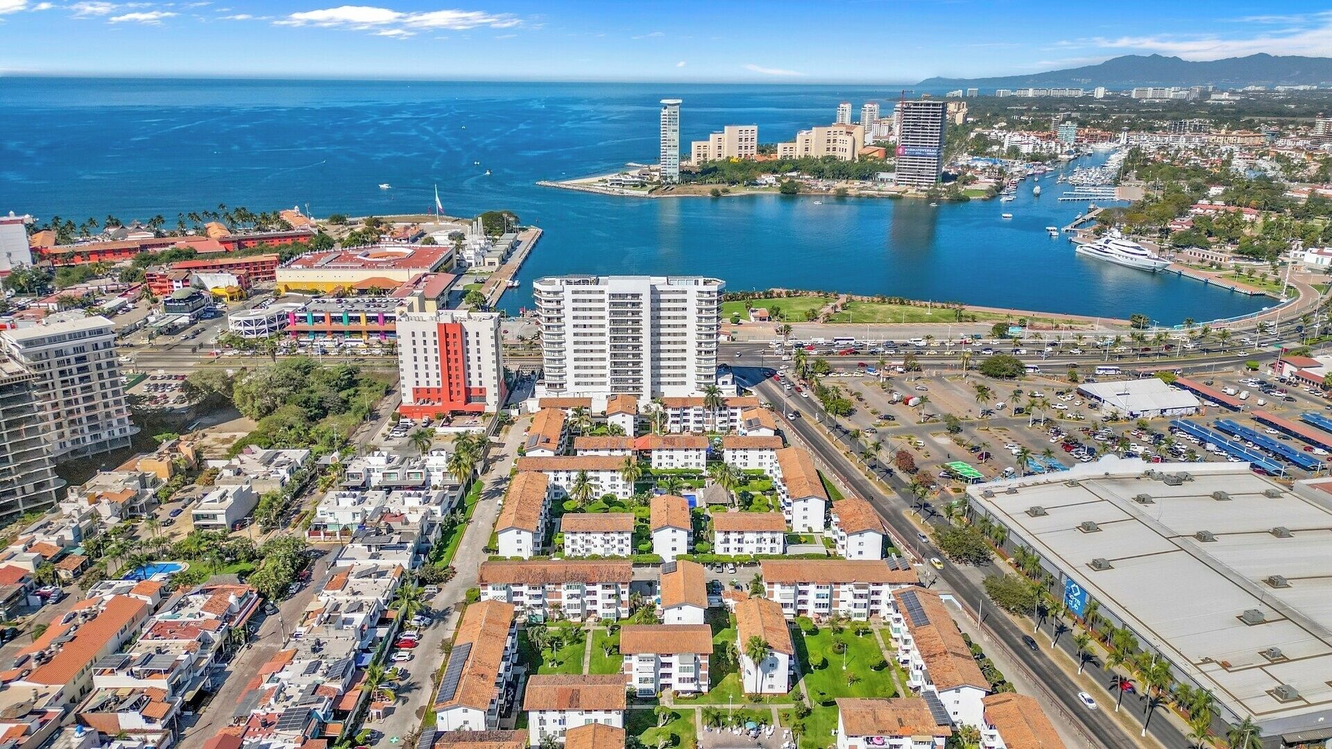 An aerial view of a coastal city with a marina, high-rise buildings, and residential areas.