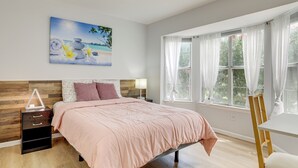 Une chambre à coucher avec un lit, une table de chevet, un bureau et une fenêtre avec des rideaux.