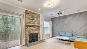 Un salon moderne avec une cheminée en pierre, un canapé, une table basse et une grande fenêtre donnant sur la forêt.