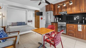 A compact kitchen with wooden cabinets, a built-in stove, and a ceiling fan. - Cozy Studio, great amenities in Versalles-Fluvial (Puerto Vallarta)