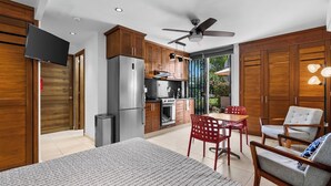A modern kitchen with wooden cabinets, a refrigerator, and a dining area with red chairs. - Cozy Studio, great amenities in Versalles-Fluvial (Puerto Vallarta)