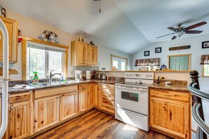 Una cucina con mobili in legno, un piano cottura e una ventola a soffitto.