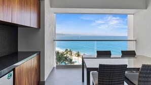 A balcony with a view of the ocean, a dining table, and wicker chairs. - Luxurious oceanfront condo (Puerto Vallarta)