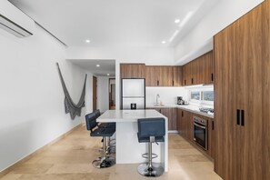 A modern kitchen with a central island, wooden cabinets, and a bar area with stools.