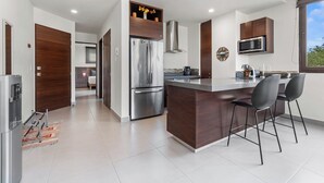 A modern kitchen with a central island, stainless steel appliances, and a view of the outdoors. - Marina view and 3 min from beach (Nuevo Vallarta)