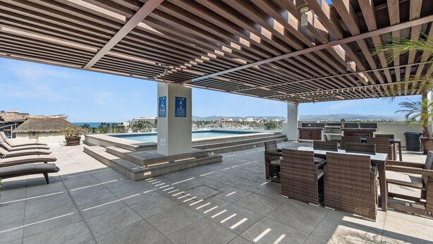 An outdoor pool area with lounge chairs, a barbecue, and a view of the ocean. - Marina view and 3 min from beach (Nuevo Vallarta)