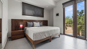 A bedroom with a wooden bed, a nightstand with a lamp, a window with blinds, and a view of palm trees. - Marina view and 3 min from beach (Nuevo Vallarta)