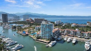 Un port de plaisance où sont amarrés de nombreux yachts, entouré de gratte-ciel et dominé par un paysage montagneux.