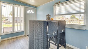Ein Zimmer mit Essbereich, ausgestattet mit Korbmöbeln, einem Fenster mit Jalousien und Blick ins Freie.