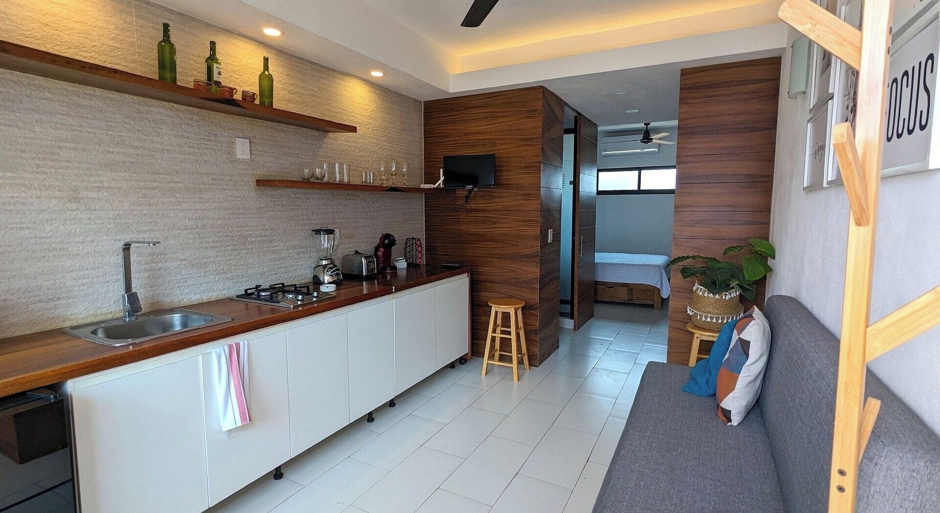 Une cuisine moderne dotée d’un plan de travail en bois, d’appareils électroménagers intégrés et d’un coin repas avec un canapé et une petite table.