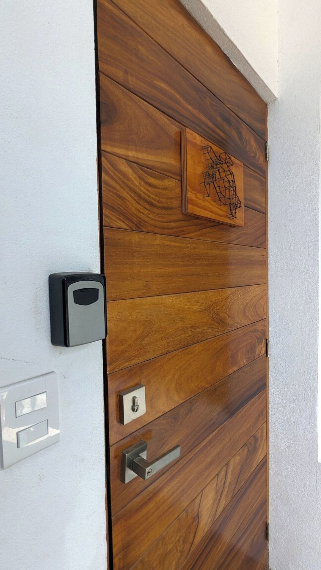 Eine Holztür mit Schlüsselloch, Schloss und Tastatur an der angrenzenden Wand.